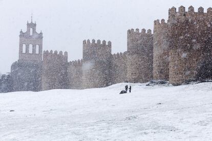 Unos niños se divierten junto a a la muralla de Ávila cubierta de nieve, el 3 de marzo de 2017.