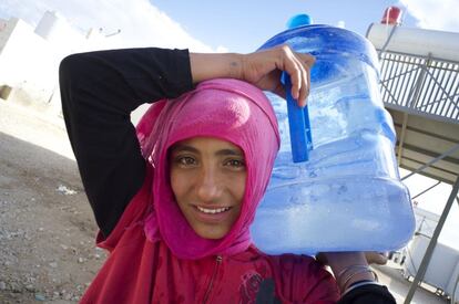Kafa, de 13 años, vuelve a la caravana donde vive su familia con una garrafa de agua que acaba de recoger de la fuente del campo de refugiados de King Abdullah Park, en Jordania. "No somos felices aquí, estamos como prisioneros", se queja. Ella procede de la ciudad siria de Dara’a y lleva 14 meses en el campo a causa de la guerra que padece su país.