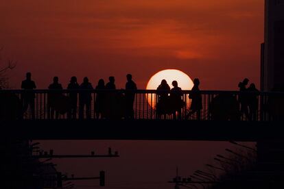 La gente observa la puesta de sol en un paso elevado en Pekín, China.