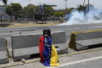 Un manifestante se cubre después de lanzar piedras a las fuerzas de seguridad en la base militar de La Carlota.