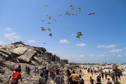 Palestinians run towards parachutes carrying aid packages airdropped over northern Gaza Strip, August 7, 2025