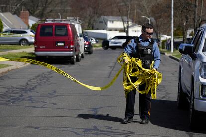 A police officer removes crime scene tape after a shooting was reported  in Levittown, Pa., Saturday, March 16, 2024.