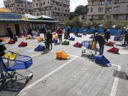 Un grupo de personas espera en fila para entrar en un supermercado de Roma. 