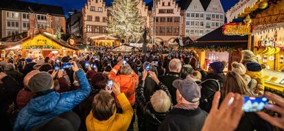 Visitantes al mercado navideño de Fráncfort toman fotos y graban vídeos con sus móviles.