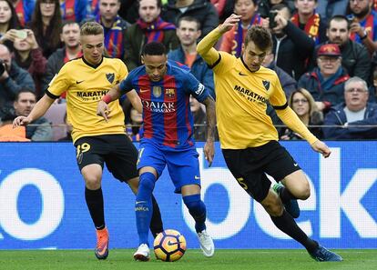 El delantero brasileño del Barcelona Neymar (centro) intenta avanzar con el balón ante Javier Ontiveros (izquierda) y Diego Llorente (derecha), del Málaga.