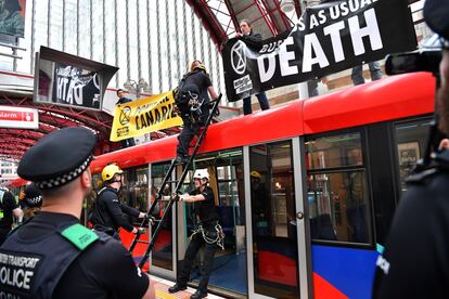 Un grupo de al menos cuatro ecologistas se subieron a lo alto de un tren de cercanías, en el barrio de Canary Wharf, y colocaron pancartas. En la imagen, la policía retira a los manifestantes de un tren mientras bloquean el tráfico en la estación Canary Wharf en Londres (Reino Unido), 25 de abril de 2019.