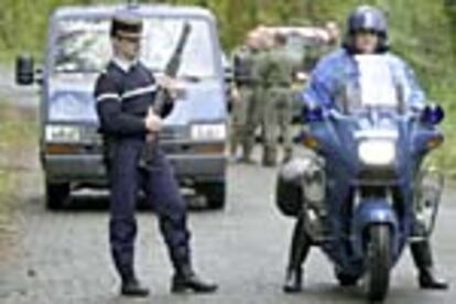 Un gendarme armado con fusil vigila, junto a otros policías franceses, la camioneta atacada por ETA el 28 de noviembre.