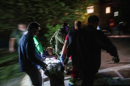 Personal de emergencias y voluntarios trasladan a una persona herida tras un ataque ruso sobre un barrio residencial de Kiev, este jueves.