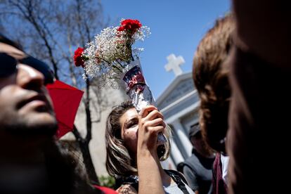 En ese imaginario colectivo, en donde se soñó con el reencuentro entre Joan y Víctor, su familia realizó la despedida de Joan, en el mismo lugar en donde se encuentra Víctor, su eterno enamorado, para que permanezcan juntos en la muerte. En la imagen, una mujer levanta un ramo de flores durante el funeral de Joan Turner. 