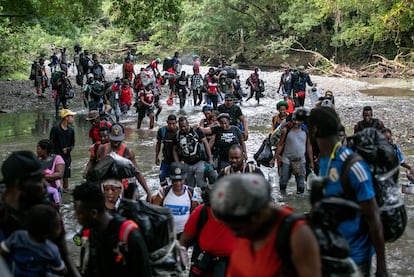 migrantes cruzan un río en la selva del Darién cerca de Acandí, en Colombia,