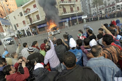 Partidarios del Movimiento Futuro, del saliente primer ministro Hariri,  lanzan soflamas contra el nuevo primer ministro,Najib Mikati, apoyado por Hezbolá, delante de un vehículo de la televisión <i>Al Yazira</i>, quemado durante las protestas.