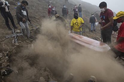 Trabajadores del cementerio Nueva Esperanza de Lima (Perú) entierran a un fallecido por coronavirus.