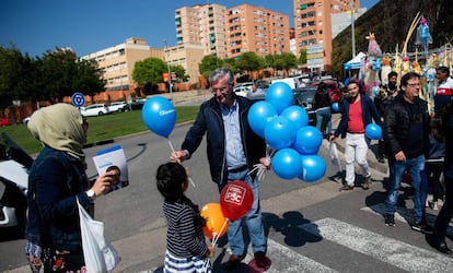 Un hombre entrega a una niña un globo con el logo del PP en una calle de Barcelona.