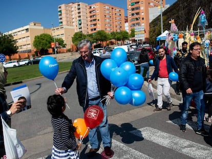 Un hombre entrega a una niña un globo con el logo del PP en una calle de Barcelona.