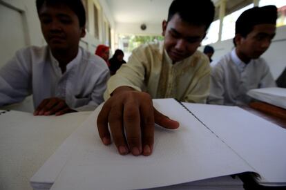 Un alumno palpa los signos en braille de un ejemplar del Corán.