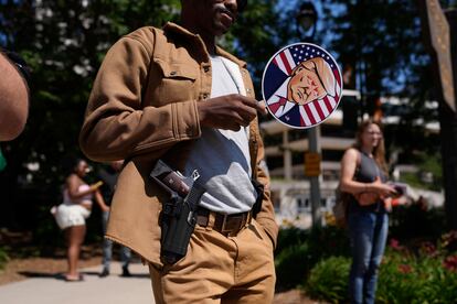 Un hombre porta una pistola y un cartel que representa al candidato presidencial republicano, Donald Trump, a las afueras de la Convención Nacional Republicana en Milwaukee el 18 de julio de 2024.