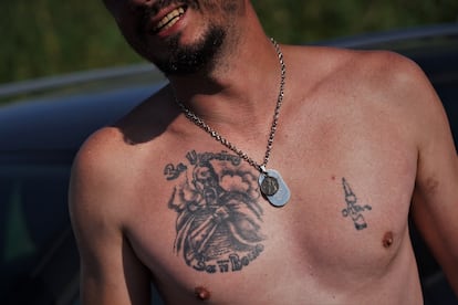 A soldier has a bullet and a Cossack tattooed on his chest. The letters read, “For Ukraine, for its freedom”