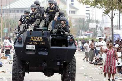 Fuerzas especiales de la policía pasan junto a refugiados en el Centro de Convenciones de Nueva Orleans.