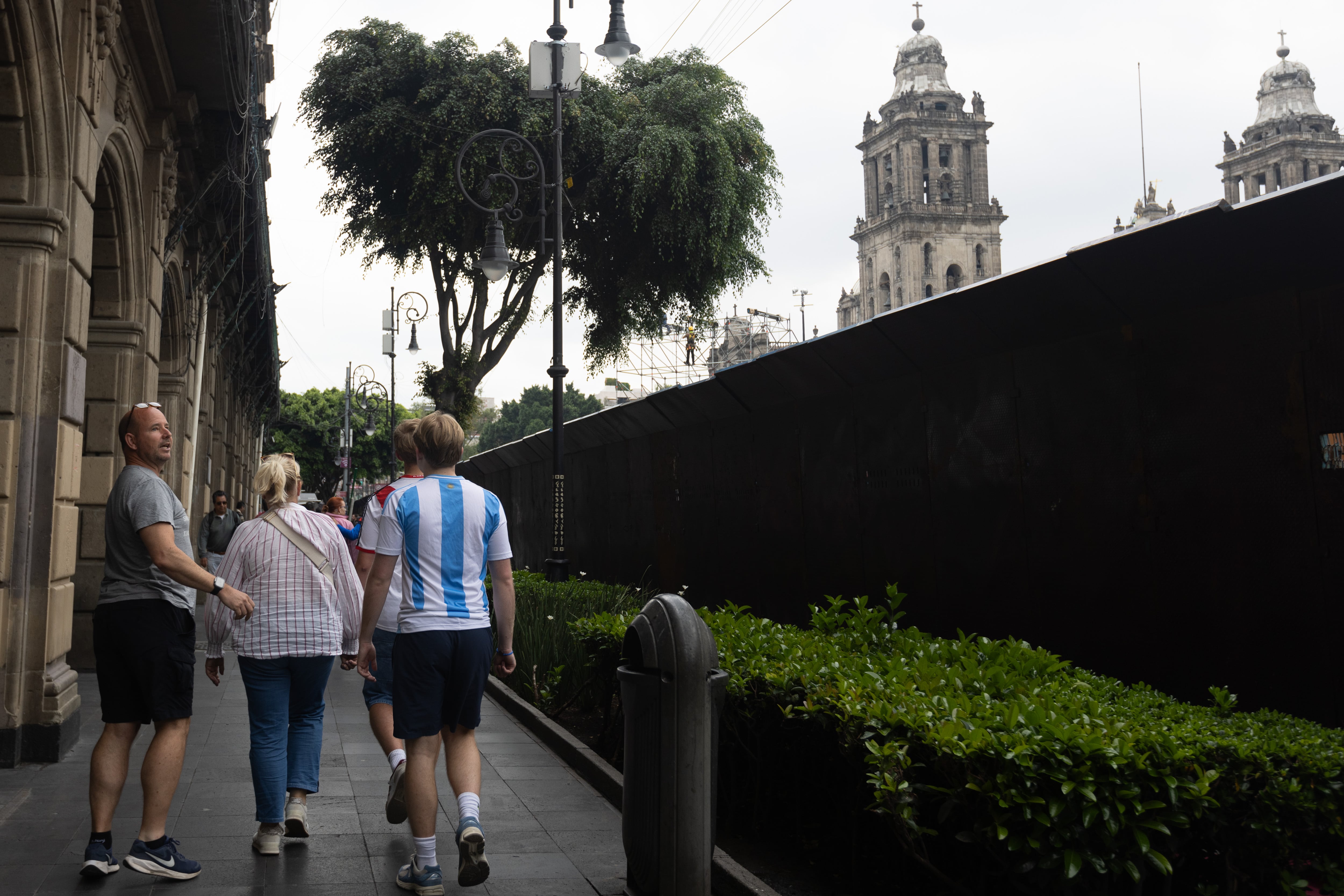 Turistas caminan afuera del zócalo capitalino, cercado con vallas de alta seguridad, este martes.