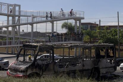 Esqueleto de um ônibus de passageiros incendiado, estacionado ao lado de uma estrada depois de o fogo ter sido apagado pelos bombeiros de Guadalajara. As autoridades no oeste do México estão pedindo aos moradores que permaneçam em casa, já que estão se empenhando em acabar com a queima de veículos bloqueando estradas em várias partes de Guadalajara. Esses bloqueios são uma resposta comum dos cartéis à detenção de membros importantes ou então ações para frustrar as operações militares e da polícia.