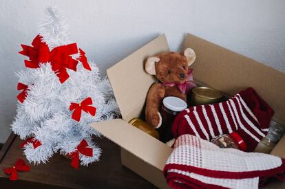 Cesta de donación preparada con ropa de abrigo, comida y juguetes para Navidad.