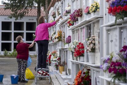 Dos mujeres colocan flores en el cementerio de la localidad sevillana de Huévar del Aljarafe, este lunes. 