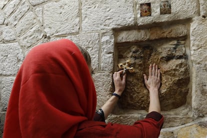 Una peregrina toca la piedra al paso de la quinta estación de la Vía Dolorsa, en el barrio musulmán de la Ciudad Vieja.