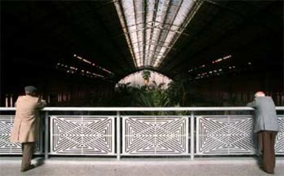 Dos ciudadanos observan desde la baranda el exótico jardín tropical creado hace diez años en la nave de la vieja estación.