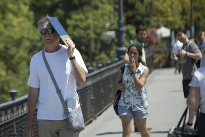 Un hombre se protege del sol en la cara con una carpeta.