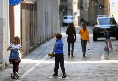 Una niña monta en patinete junto a un niño que carga un monopatín, el miércoles en Milán.