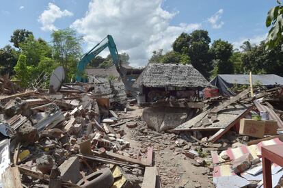 Una grúa destruye este 12 de junio parte de una tienda dañada en el seísmo en Gangga (Lombok).