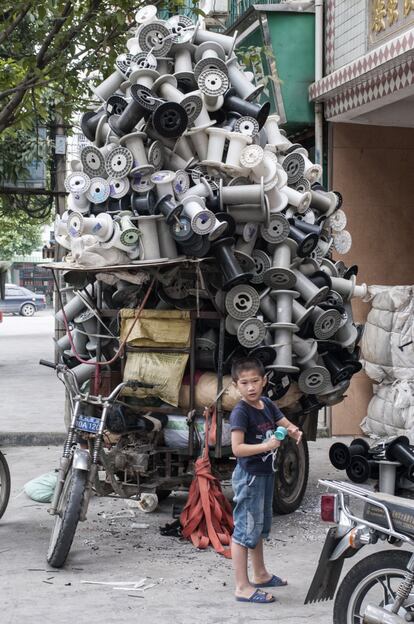 Un niño juega frente a un triciclo repleto de bobinas de plástico para su reciclado en Guiyu. En 2016, el 56% de toda la basura que se movió por el mundo acabó en China.