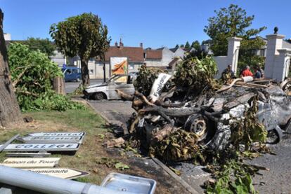 Un coche calcinado frente a la puerta de la comisaría atacada este domingo en Saint-Aignan.