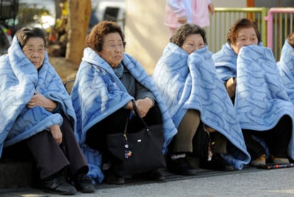 Varias mujeres esperan en la calle tras ser evacuadas de un edificio en Tokio.