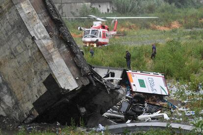 Un helicoptero de los servicios de emergencia y un equipo de rescate, rastrean los escombros del puente Morandi en busca de víctimas.