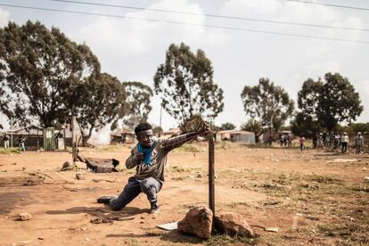 Un manifestante utiliza un tirachinas para lanzar una piedra a los miembros de la policía antidisturbios durante una manifestación por la prestación de servicios y vivienda en la comunidad de Finetown, en la localidad de Ennerdale (Sudáfrica).