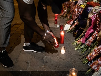 Buba enciende una vela junto a las flores en homenaje a Conchi en la plaza de Tirso de Molina.