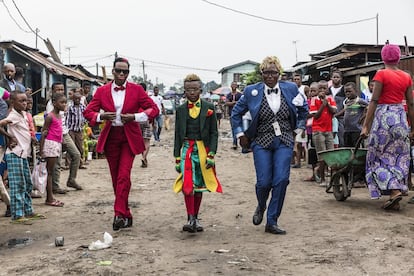 Alguien que sigue la corriente <em>sape</em> es conocido como <em>sapeur</em>. em>Sapeuse</em> es el nombre para mujer. En esta imagen tomada en Brazaville en 2017 posan, de izquierda a derecha: Ntsimba Marie Jeanne, empresaria de 52 años y <em>sapeuse</em> durante 20; Okili Nkoressa, estudiante de 10 años y <em>sapeur</em> durante cinco. Viste traje y camisa de Yves Saint Laurent, falda escocesa de estilo congoleño, gafas de Cartier, pajarita y guantes del Congo, cinturón y calcetines de Pierre Cardin, zapatos de Churchill UK y lazos alrededor de la cintura de Massimo Dutti, H&M, Nek, Trikira, Pierre Balmain, Sald Fried y Ascot. "Mi prenda favorita es mi traje de Yves Saint Laurent que llevo hoy", asegura. En último lugar, Judith Nkoressa, mujer policía de 39 años y <em>sapeuse</em> durante 18. Viste traje de Rubens, camisa de Red Italyon, chaleco de Was Kowaum Keenly, pajarita de Pierre Cardin, sombrero de Feutre Englais, gafas de Italia y zapatos de JM Weston.