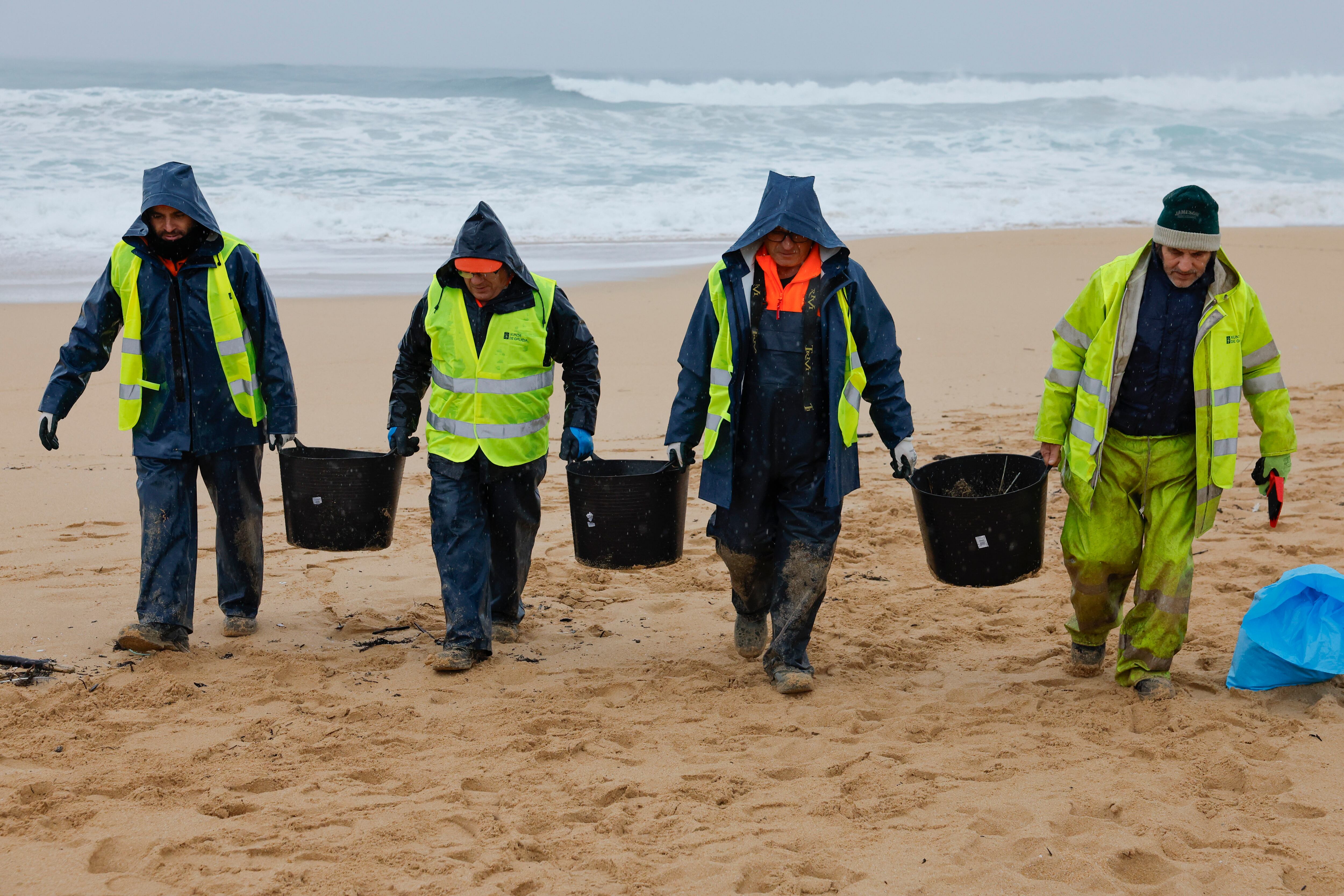 Operarios de empresas contratadas por la Xunta retiran los pellets en la playa gallega de O Vilar, en el parque natural de Corrubedo, A Coruña. 