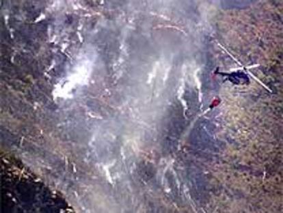 Un helicóptero lanza agua sobre el incendio de Buñol y Chiva.