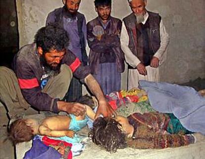 Un grupo de hombres vela los cadáveres de cuatro de los niños muertos durante los bombardeos.