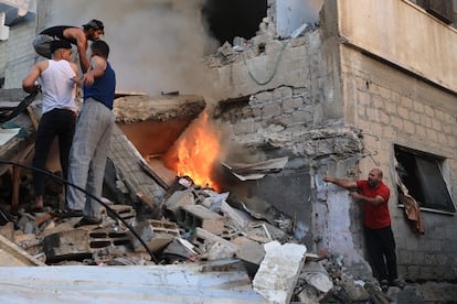 Varios hombres buscaban supervivientes entre las llamas de un edificio derrumbado tras un bombardeo israelí sobre Jan Yunis, este sábado.  