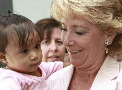 Esperanza Aguirre con una niña en brazos en la reunión que mantuvo ayer con asociaciones de peruanos.