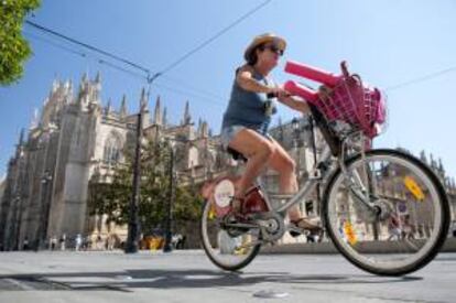 Una chica pasea en bici de alquiler por el centro de Sevilla.