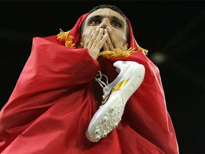 El marroquí Hicham El Guerruj celebra su victoria en la prueba de 5.000 metros envuelto en la bandera de su país en los JJ OO de Atenas 2004.