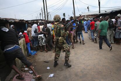 MONROVIA, LIBERIA - AUGUST 20: A Liberian Army soldier, part of the Ebola Task Force, pushes back local residents while enforcing a quarantine on the West Point slum on August 20, 2014 in Monrovia, Liberia. The government ordered the quarantine of West Point, a congested seaside slum of 75,000, on Wednesday, in an effort to stop the spread of the virus in the capital city. Liberian soldiers were also sent in to the seaside favela to extract West Point Commissioner Miata Flowers and her family members after residents blamed the government for setting up a holding center for suspected Ebola patients to be set up in their community. A mob overran and closed the facility on August 16. The military also began enforcing a quarrantine on West Point, a congested slum of 75,000, fearing a spread of the epidemic. The Ebola virus has killed more than 1,200 people in four African nations, more in Liberia than any other country. (Photo by John Moore/Getty Images)