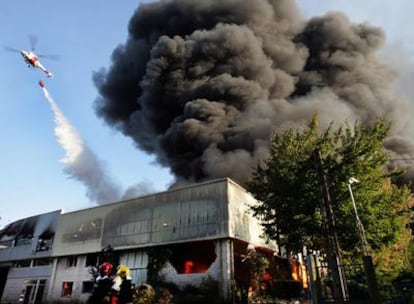 Un helicóptero trata de sofocar el incendio en la nave de cordelería de la empresa JJ Chicolino, en Boiro.