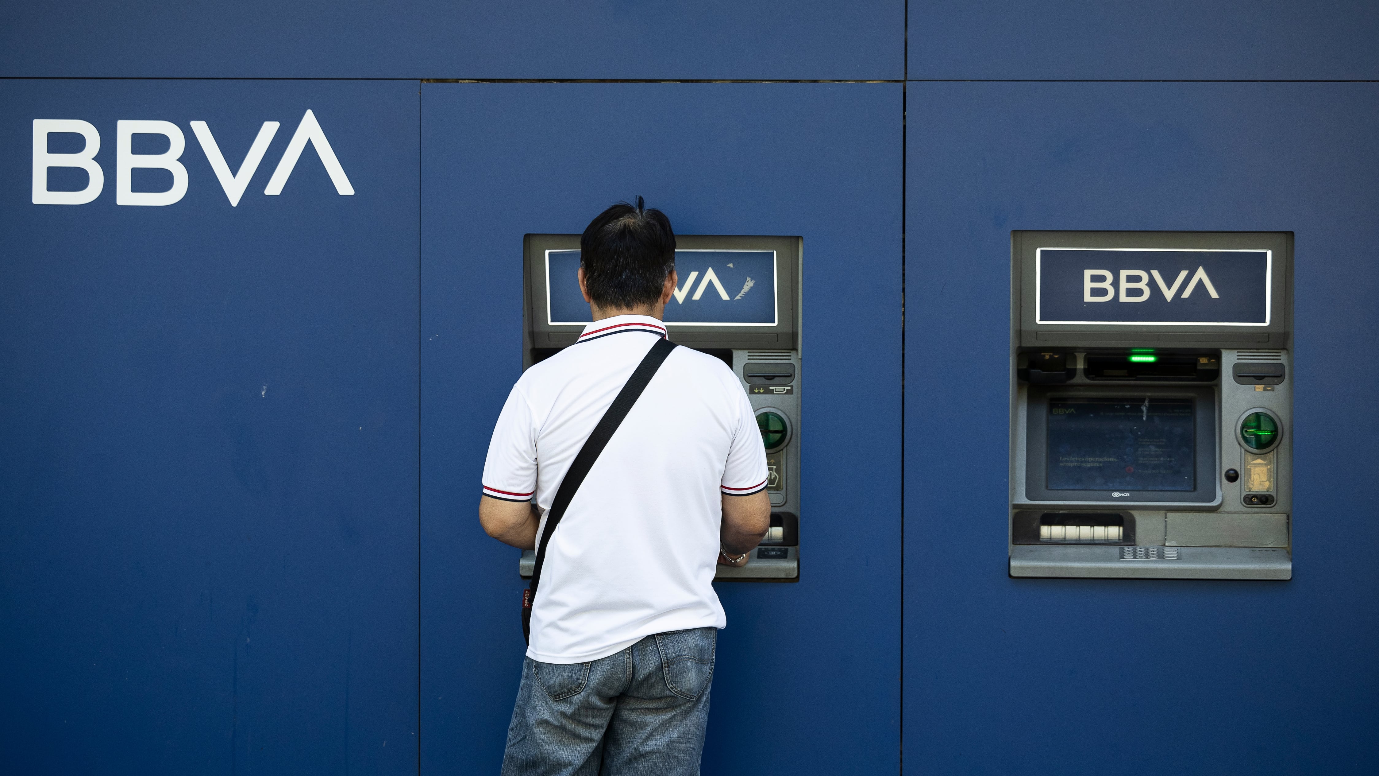 Un hombre saca dinero del cajero en una oficina bancaria del BBVA de la Gran Vía.  