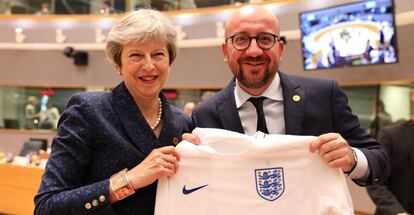 El primer ministro belga, Charles Michel, recibe de Theresa May la camiseta de la selección inglesa en la cumbre europea.