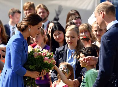 El príncipe Guillermo de Inglaterra observa cómo una niña le regala un ramo de flores a su esposa Kate Middleton, durante su visita ala organización benéfica Strassenkinder.